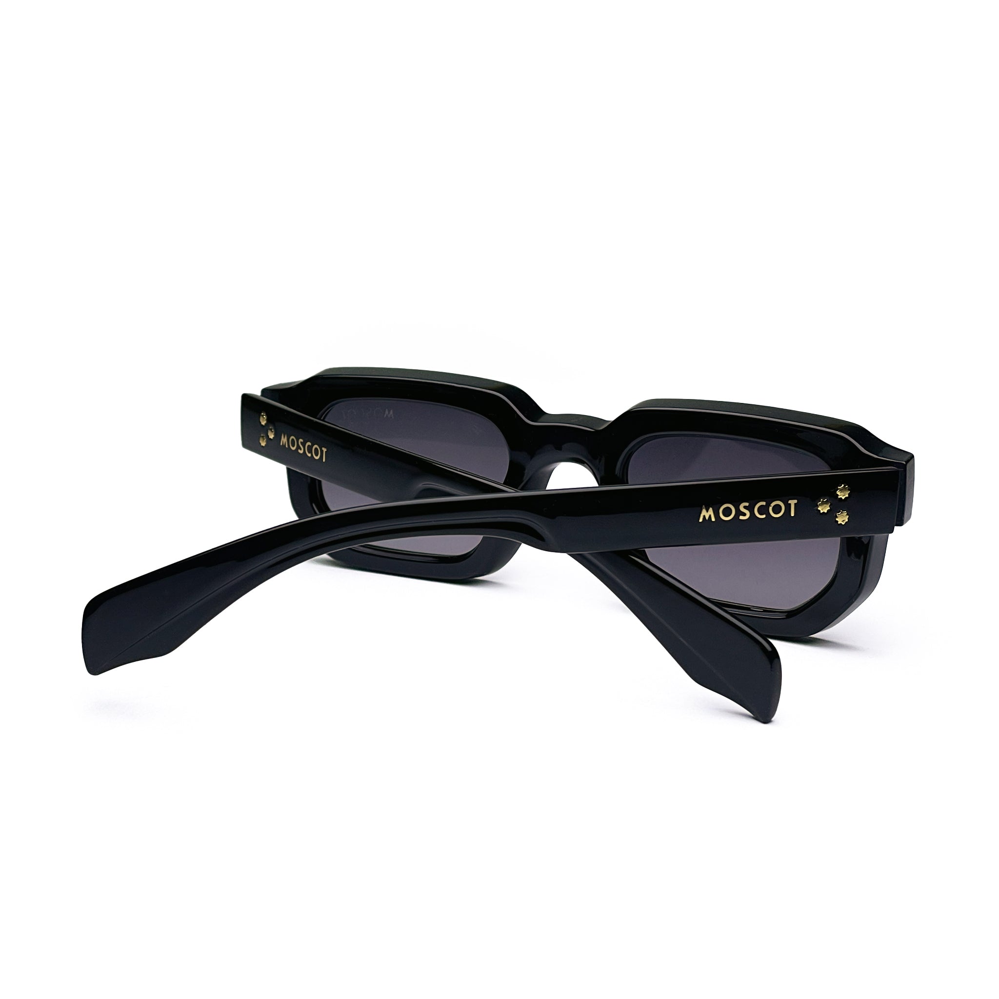 Black rectangular sunglasses with thick frames, gold accents, and tinted lenses