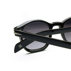 Close-up of black round sunglasses with dark lenses and silver accents on arms