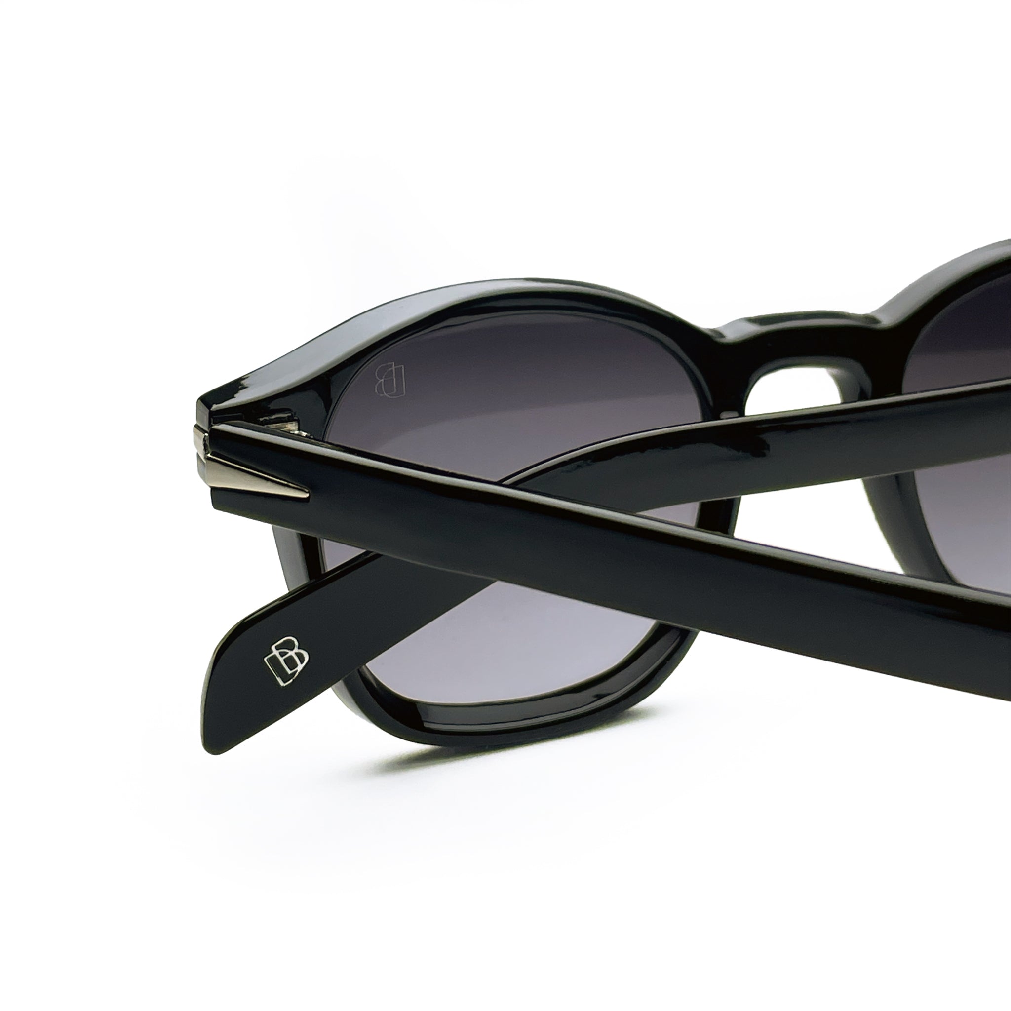 Close-up of black round sunglasses with dark lenses and silver accents on arms