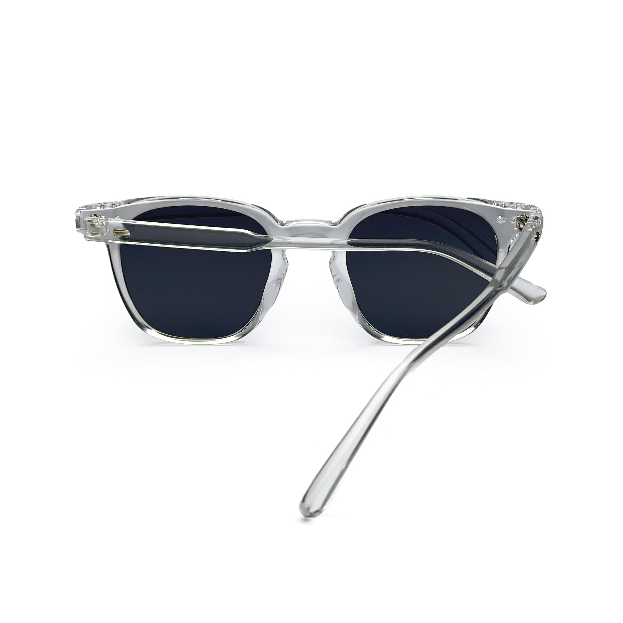 Clear frame sunglasses with dark lenses, one temple arm crossed, on white background